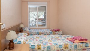 Un dormitori amb dos llits, una finestra i una làmpada.