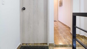 A hallway with a wooden door labeled '201', a black metal doormat, and a staircase with a black railing. - Two Bedroom Two Hot tub balcony doorman Part time AC.  Poblado (Medellin)