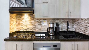 A kitchen with a gas stove, a coffee maker, and a dishwasher. - Two Bedroom Two Hot tub balcony doorman Part time AC.  Poblado (Medellin)