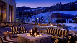 An outdoor seating area with a fire pit, lounge chairs, and a view of a ski resort in the background. - Beaver Creek Park Hyatt 3 Bedroom Residence (Avon)