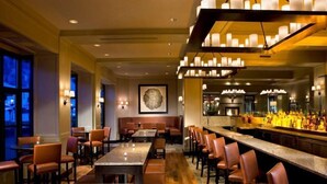 A bar area with multiple seating options, including tables and bar stools, and a counter with a variety of bottles. - Beaver Creek Park Hyatt 3 Bedroom Residence (Avon)