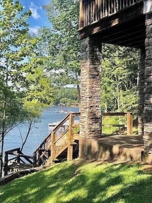 A stone building with a wooden deck and stairs leading to a dock by a lake. - Waterfront house, Minutes to Auburn, Boat slip. (Dadeville)