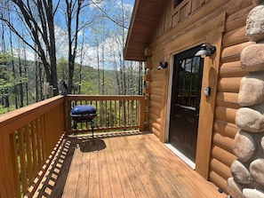 A wooden cabin with a deck, a door, and a mailbox.