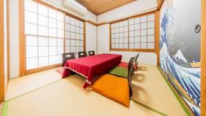 Une pièce de style japonais traditionnel, avec un sol recouvert de tatamis, un futon rouge et des paravents en papier de riz (shoji).