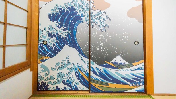Une pièce de style japonais traditionnel, dotée d’une porte coulissante en papier de riz (shoji) ornée d’une peinture représentant une vague.