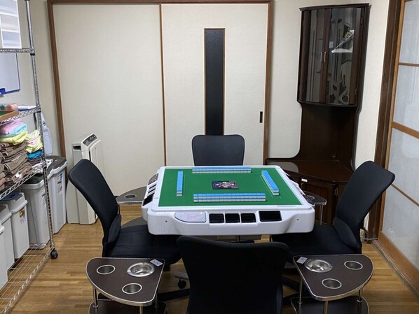 A room with a green and white table, four black chairs, a cabinet, and a shelf with folded towels. - Hikari no Yado - Detached house for rent in Anan City, Tokushima Prefecture (徳島県)