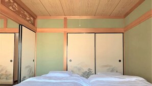A bedroom with a wooden ceiling, a bed with white bedding, and a sliding door with a traditional design. - Hikari no Yado - Detached house for rent in Anan City, Tokushima Prefecture (徳島県)
