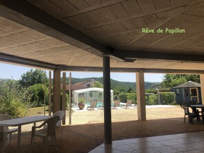 Un patio couvert avec vue sur une piscine et une serre.