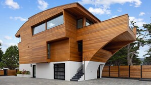 Een modern, meerlaags huis met een schuin dak en houten gevel.