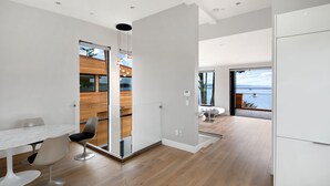 Een modern interieur met een eethoek, een keuken en uitzicht op zee.