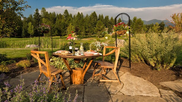 Un tavolo di legno con sedie posizionato all'aperto, immerso in un giardino ricco di piante e fiori.
