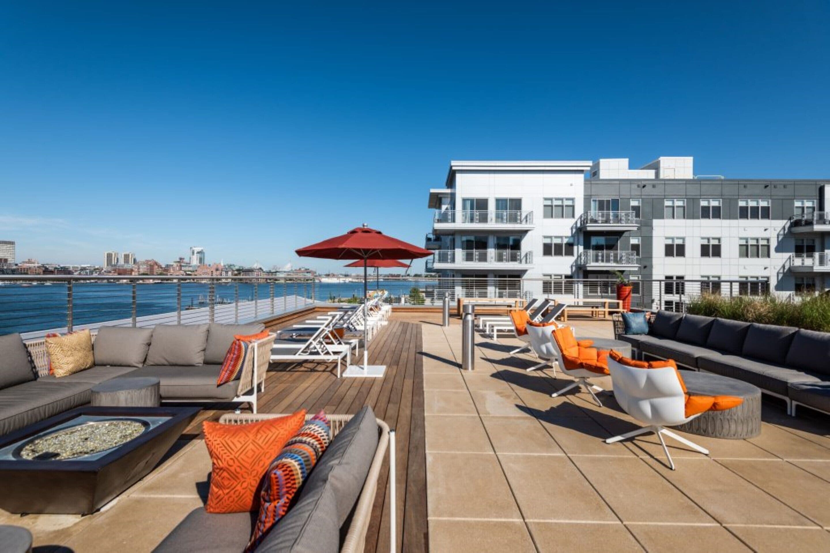 Terraza en la azotea con mobiliario exterior, una chimenea y vistas del horizonte urbano y el agua.