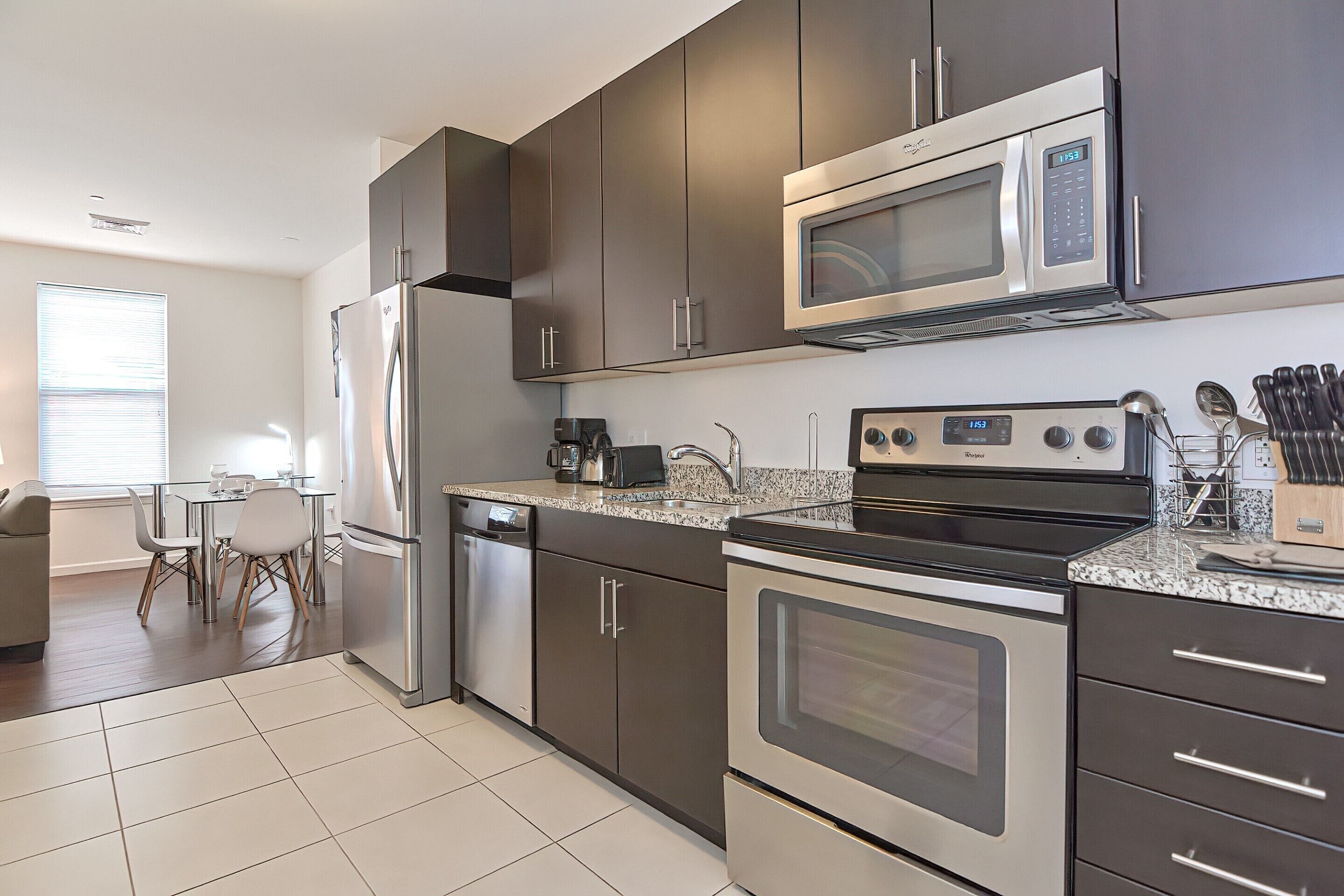 A modern kitchen with stainless steel appliances, dark cabinets, and a granite countertop.