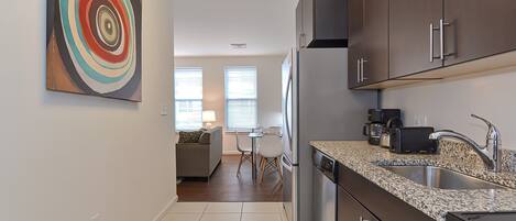 Una cocina moderna con encimeras de granito, electrodomésticos de acero inoxidable y muebles oscuros.
