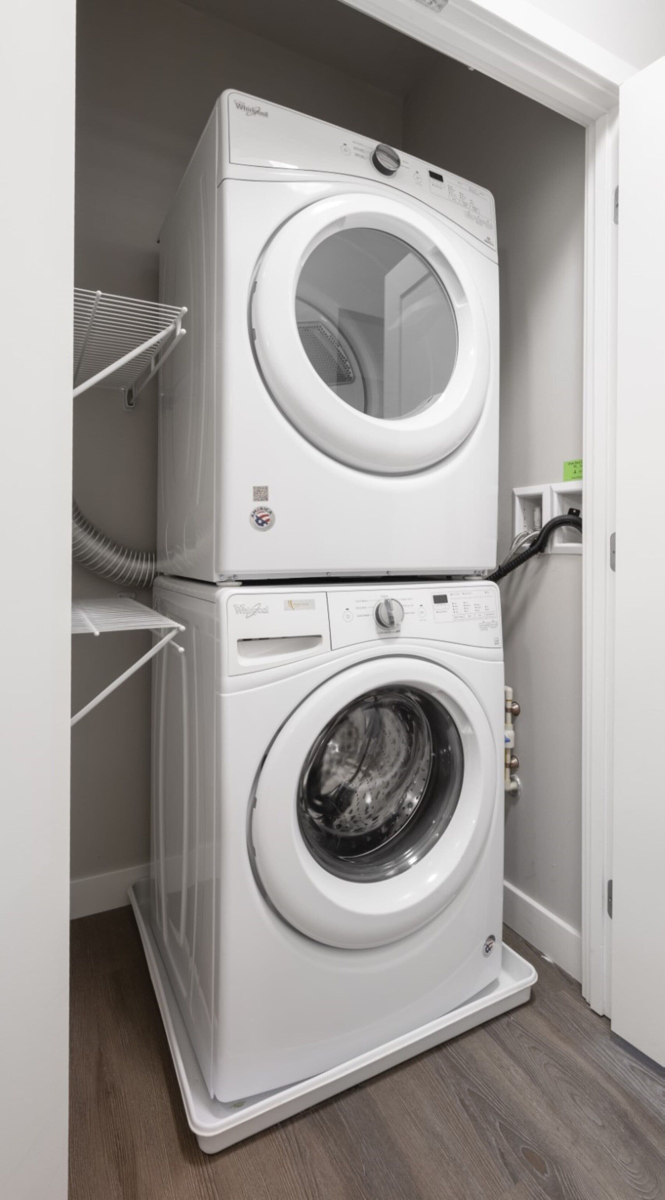 A stacked washer and dryer unit in a laundry room with a shelf above the dryer.