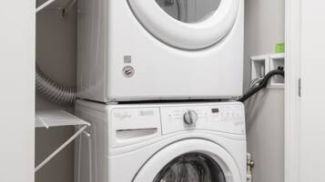 Una lavadora y secadora apiladas en un cuarto de lavado, con un estante sobre la secadora.