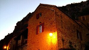 A stone building with a single window and a lit lamp post. - Bed and breakfast facing the Millau viaduct and the Tarn river magnificent view (COMPREGNAC)