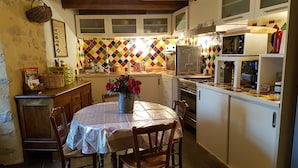 A kitchen with a dining table, chairs, a refrigerator, stove, and a microwave. - Bed and breakfast facing the Millau viaduct and the Tarn river magnificent view (COMPREGNAC)