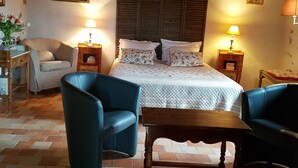 A cozy room with a bed, two chairs, a small table, and a wooden ceiling. - Bed and breakfast facing the Millau viaduct and the Tarn river magnificent view (COMPREGNAC)