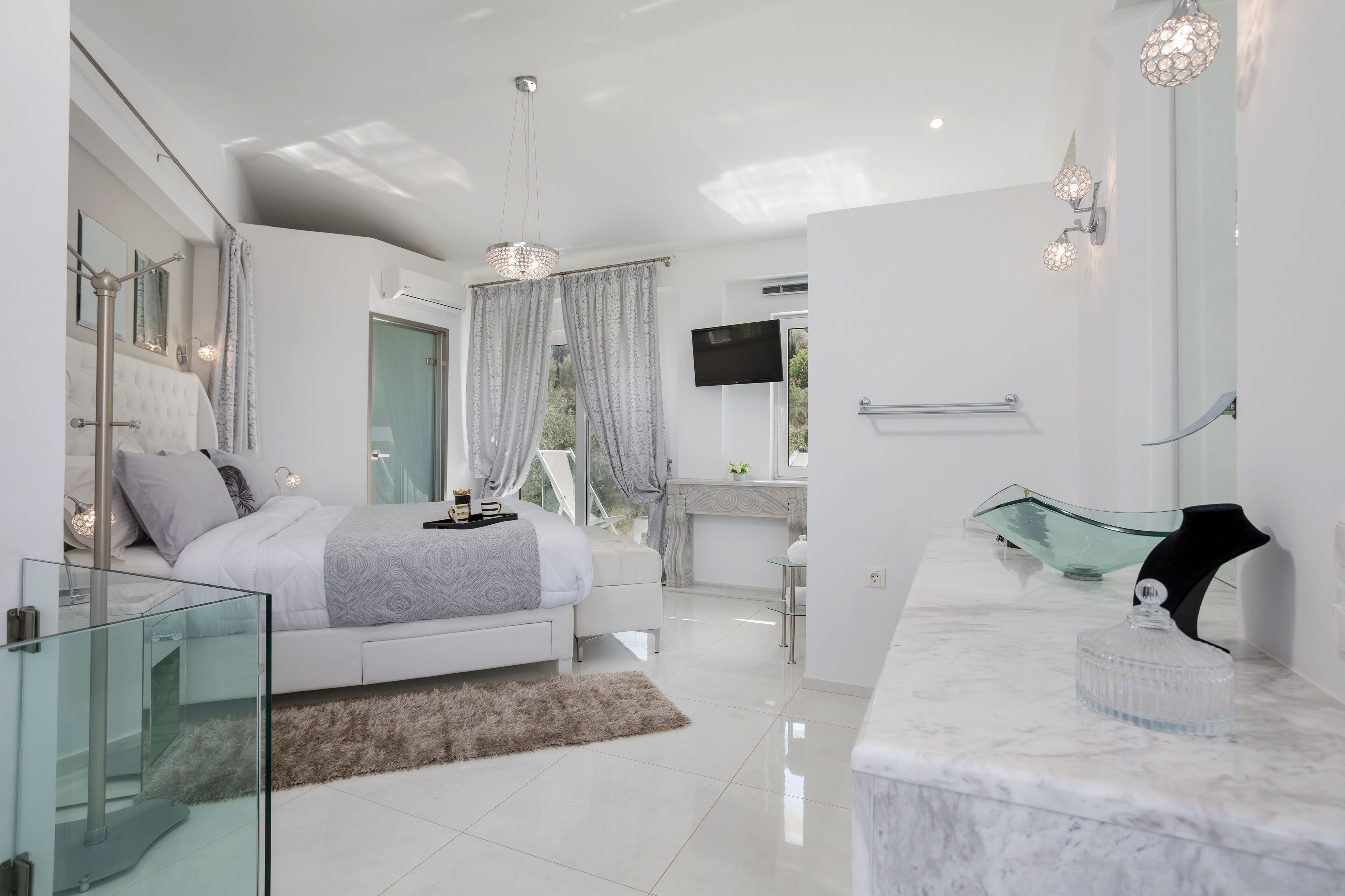 A modern bedroom with a glass shower enclosure, a marble bathroom vanity, and a large bed with a fluffy rug.
