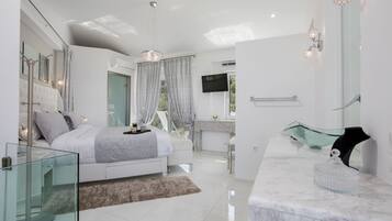 A modern bedroom with a glass shower enclosure, a marble bathroom vanity, and a large bed with a fluffy rug.