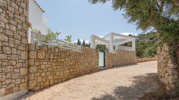 Um muro de pedra com um portão branco e uma estrutura de pérgola.