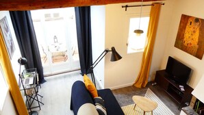 A living room with a sofa, a TV, a lamp, and a small table. - 1 Bedroom with terrace - Wifi, Air Conditionning / 1 to 5 People (Aix-en-Provence)