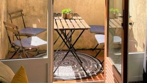 A small patio area with a wooden table and chairs, a patterned rug, and a potted plant. - 1 Bedroom with terrace - Wifi, Air Conditionning / 1 to 5 People (Aix-en-Provence)
