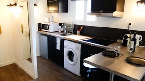 A compact kitchen with a washing machine, microwave, and a small dining area with stools. - 1 Bedroom with terrace - Wifi, Air Conditionning / 1 to 5 People (Aix-en-Provence)