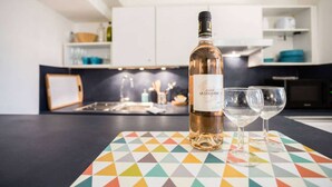 A bottle of wine and two glasses on a colorful table in a modern kitchen. - 1 Bedroom Flat Quartier Rotonde - Lift, Wifi, Air Conditionning / 1 to 6 People (Aix-en-Provence)