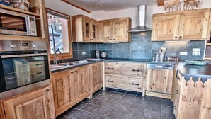 Una cocina con armarios de madera, un horno de acero inoxidable y una encimera negra.
