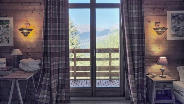 Ein gemütliches Zimmer mit großem Fenster, Karosospendern und zwei Wandleuchten.