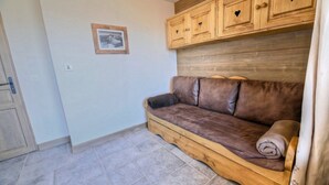A room with a wooden bench, a brown leather sofa, and a wooden cabinet with heart-shaped cutouts. - Le Cairn, stunning 14 person, 7 bedroom chalet with sauna & games room (Peisey Nancroix)