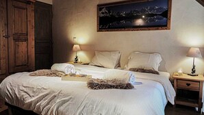 A bedroom with a large bed, two bedside tables, a nightstand, a wooden wardrobe, and a framed picture on the wall. - Le Cairn, stunning 14 person, 7 bedroom chalet with sauna & games room (Peisey Nancroix)