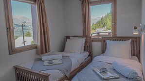 A room with two beds, wooden headboards, and large windows with curtains. - Light, bright 2 bed apartment for 6 people with lovely views and close to lifts (Landry)