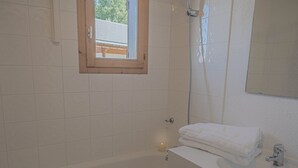 A bathroom with a bathtub, a window, a mirror, and a towel rack. - Light, bright 2 bed apartment for 6 people with lovely views and close to lifts (Landry)