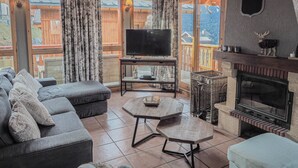 A cozy living room with a sofa, a coffee table, a fireplace, and a television.