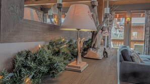 A wooden table with a lamp, a Christmas tree, and a rustic wall decoration.