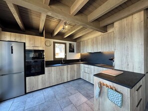 Una cocina moderna con muebles de madera, un refrigerador de acero inoxidable y una encimera negra.