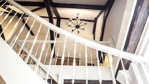 Un escalier en colimaçon avec des balustrades blanches et des poutres en bois foncé.
