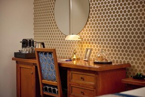Ett hotellrum med ett skrivbord i trä, en spegel, en lampa och en tapet med mönster.