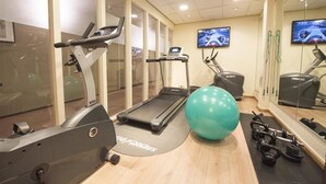 Une salle de sport équipée de tapis de course, d’un vélo d’appartement et de ballons d’exercice.