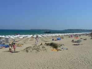 En strand med parasoller og mennesker.