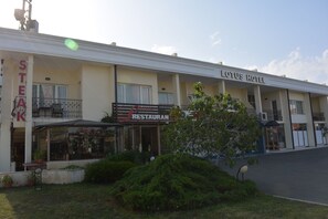 Un hotel con restaurante en la planta baja, un letrero que anuncia un restaurante de carne y un cielo despejado.