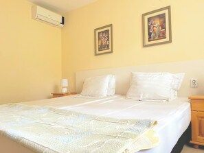 Habitación de hotel con cama, dos mesitas de noche, una lámpara y dos cuadros en la pared.