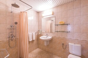 Un baño con ducha, lavamanos, inodoro y espejo.
