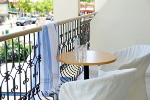 Un balcón con una mesa redonda y dos sillas, baranda de metal y vista a la calle.