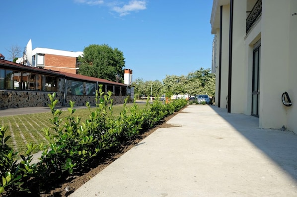 Un sendero pavimentado bordeado por vegetación y edificios con fachada de piedra y diseño moderno.
