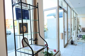 A hotel reception area with a glass partition, a framed award, and a view of the street outside.