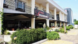 Un restaurante con terraza, balcón y fachada de edificio moderna.